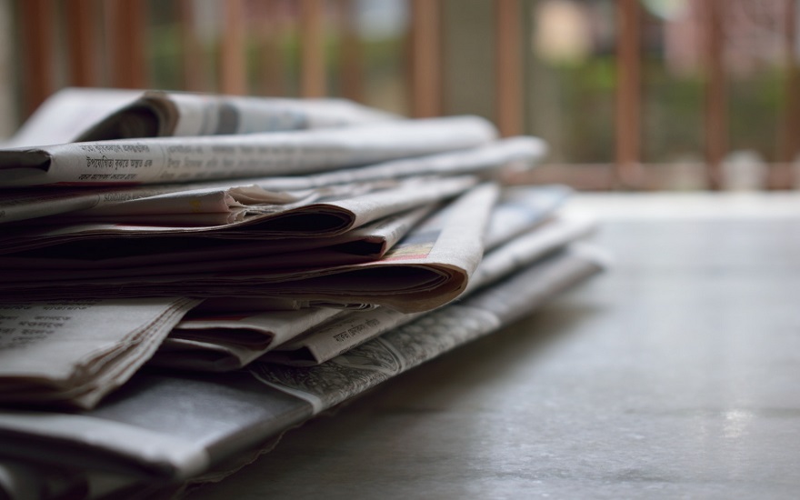 several newspapers piled up on a table