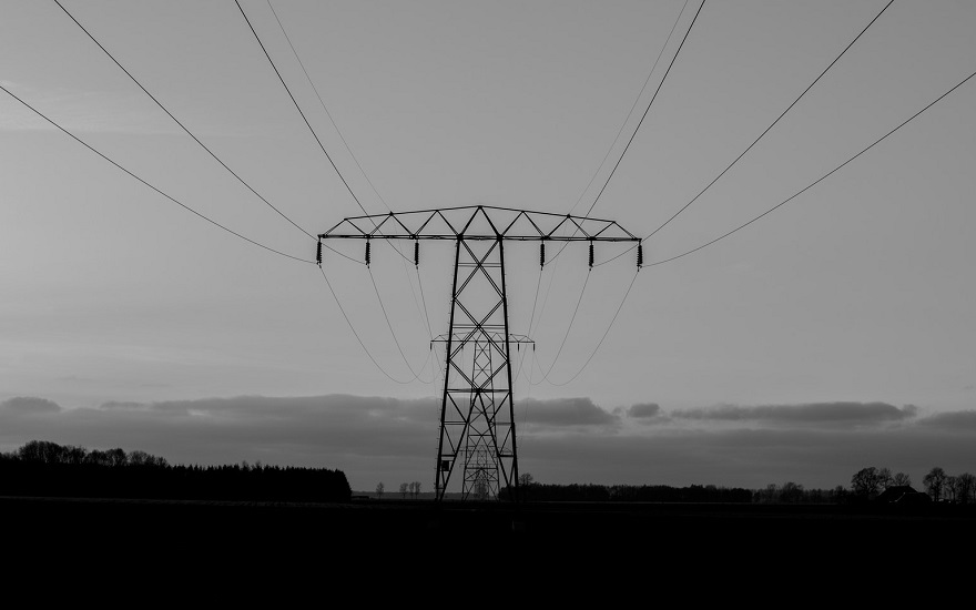 greyscale image of electricity pylon in a field