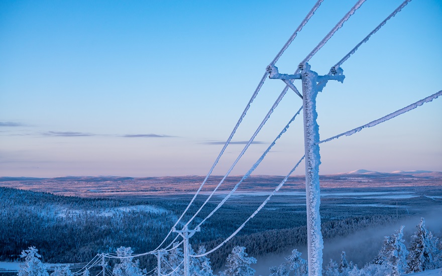 electricity pylon in winter with ice on the pylon and a bright blue background