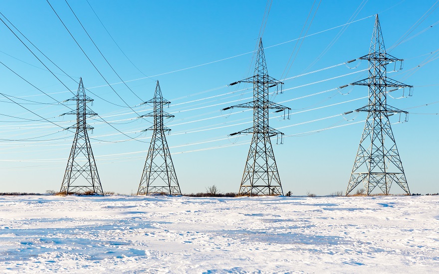 four electricity pylons in snowy field with sunny blue sky